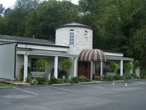 A white building with a red awning and a parking lot, offering car booking for wine tours.