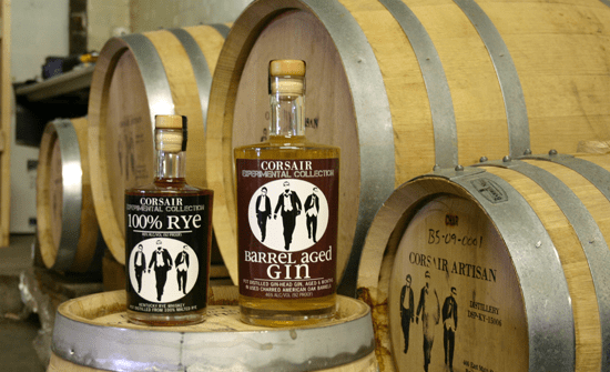 A bottle of whiskey sits on a wooden barrel.