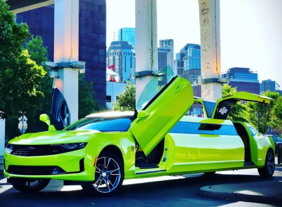 A lime green chevrolet camaro is parked in front of a transportation service building.