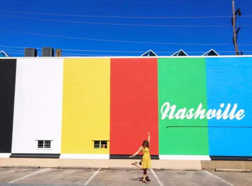 A woman standing in front of a colorful building with a Nashville transportation service written on it.