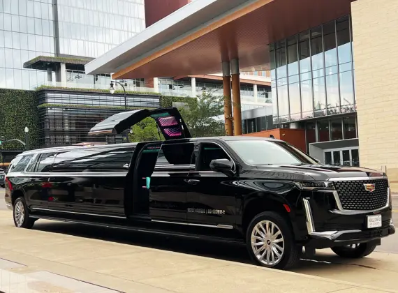 A black Cadillac Escalade limo, one of the finest choices in the transportation service industry, is parked in front of a building.