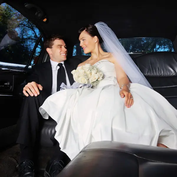 A bride and groom sitting in the back of a limo.