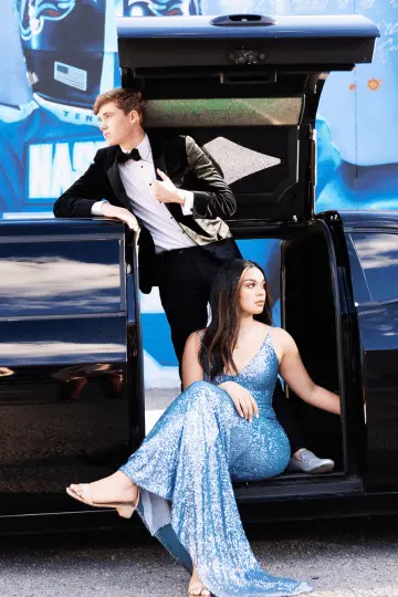 A girl in a stylish blue outfit and a boy in a black outfit are arriving to a prom party in a brand-new limousine