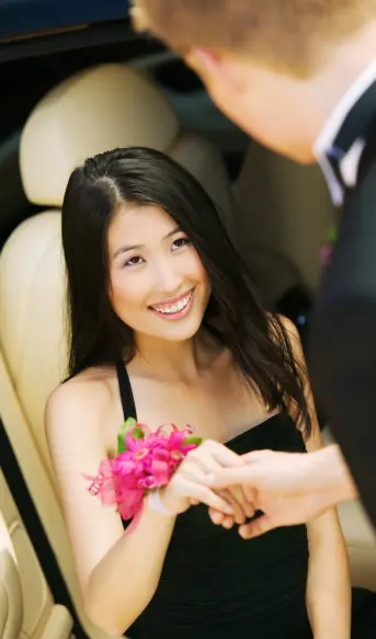 A girl sitting in a luxury car and smiling on her prom party