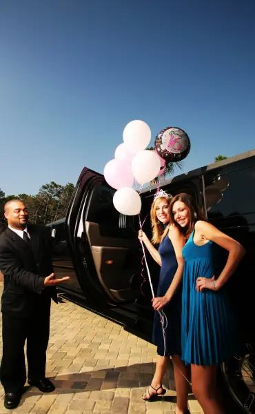 2 girls are thrilled after seeing their chauffeur with a black hummer limousine